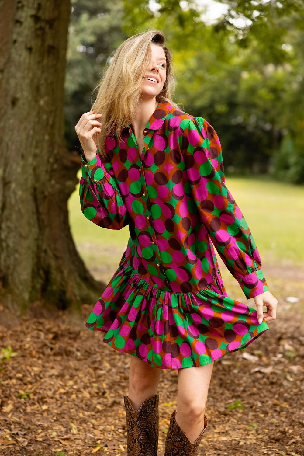Double A Lola Dress in vibrant pink and green polka dot print with long sleeves and ruffled mini hem, styled with tall boots.