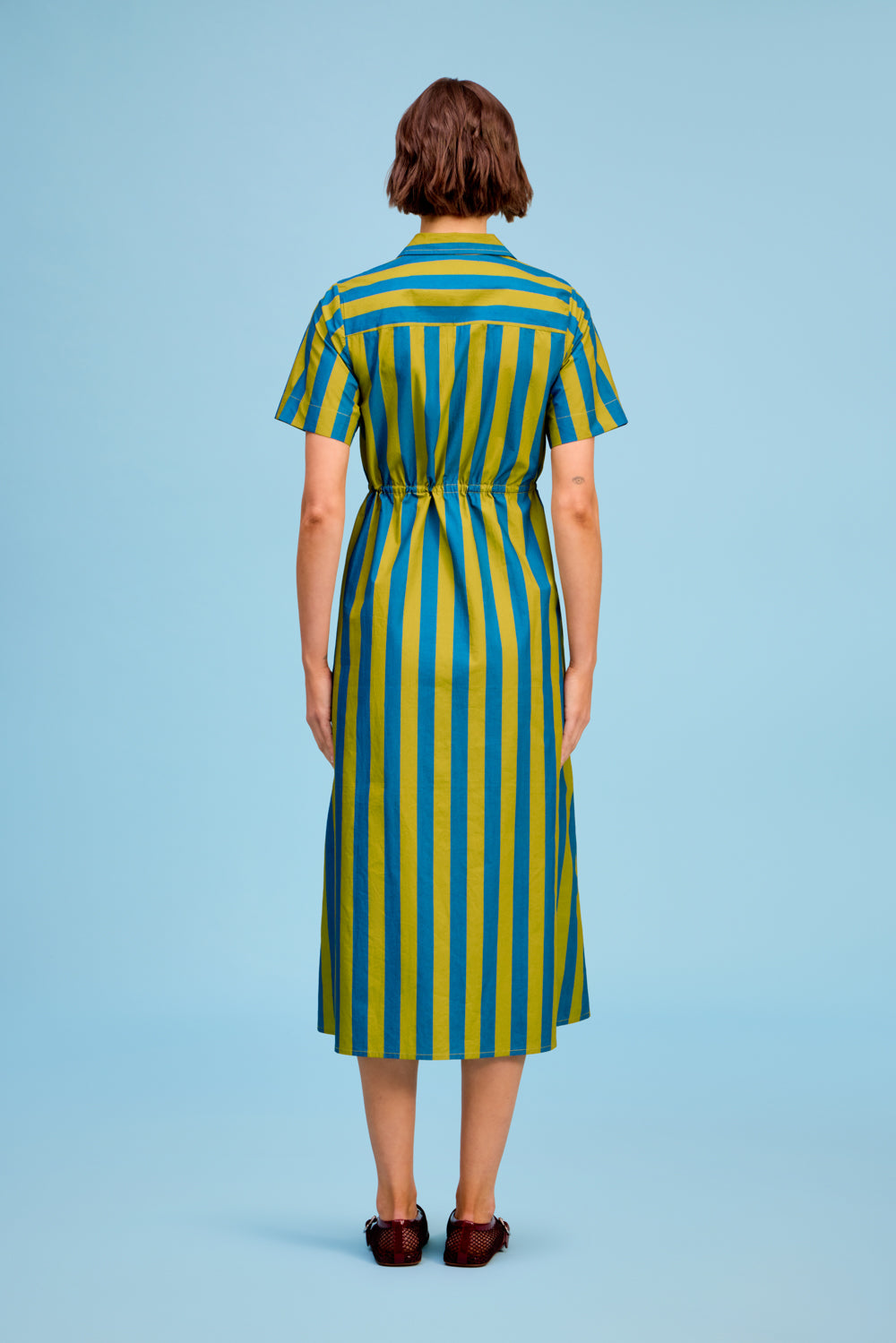 Back view of the LIVRO Sutton striped midi shirtdress featuring colorful vertical stripes and a flowing skirt.
