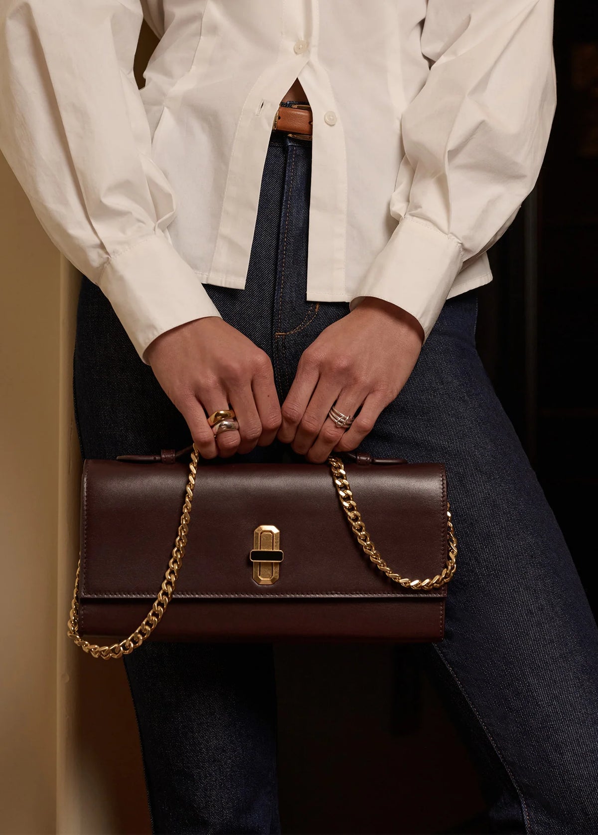 Favorite Daughter Heirloom Clutch chocolate brown handbag with gold chain styled with white blouse and denim
