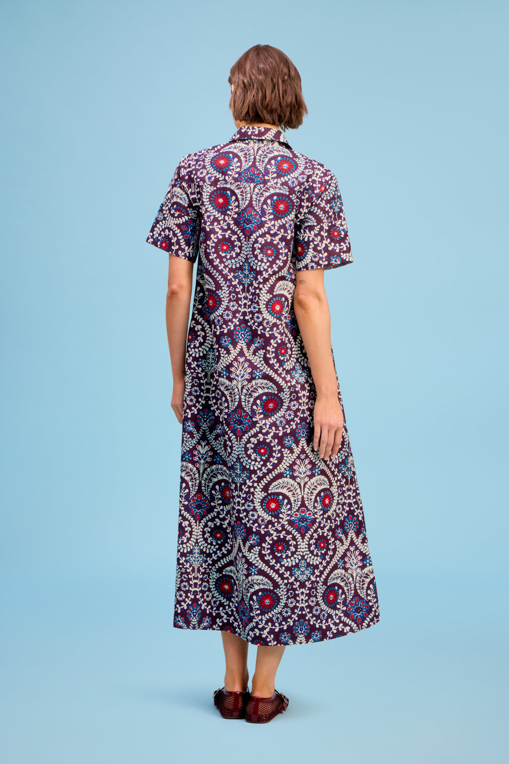 Back view of LIVRO Gibbons Dress featuring an intricate blue, pink and burgundy medallion print and relaxed long silhouette.